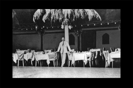 The club’s décor consisted of bamboo, rattan and leatherette wall coverings, suspended satin cloth ceilings, and heavy draperies. Here, the Grove’s Maître d' poses in front of a support column made to look like a palm tree in the main dining room. The interior finishes were supposed to be flame resistant, but the club owner cut corners and avoided applying flame retardant chemicals in order to save money—a particularly critical omission with regards to the satin.
