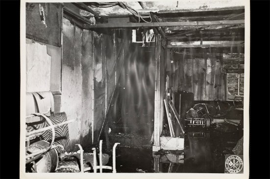 Like previous renovations to the nightclub, the Melody Lounge was constructed without building permits. It was fashioned out of a basement storage room and built with a lone public exit from the basement—a narrow, 4-foot-wide staircase. In addition to its tropical décor, a blue satin ceiling was suspended 18 inches from the concrete floor above to help create an intimate space. The room’s lighting was comprised largely of low-wattage bulbs placed within cocoanut shells. On the night of November 28, 1942, after a busboy lit a match to search for an unscrewed bulb, the cloth ceiling caught fire. Partially combusted gasses emanating from the oxygen-deprived lounge followed the fleeing occupants up the staircase. Surprisingly, most of the damage to the lounge’s décor was concentrated up high; the upholstered furniture was left largely intact.