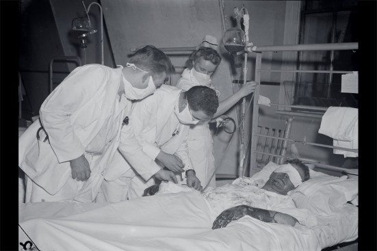 Here, a burn victim is receiving blood plasma. Due to the number of injured Grove patrons admitted to area hospitals, medical personnel were forced to adopt new methods of care regrading burns and internal injuries—some methods had been well tested, while others had not. The one silver lining of this calamitous event is that methods honed for treating burn victims (such as using antibiotics, skin grafting, and treating the affected skin areas with petroleum jelly—Vaseline) would be used to help burn victims, both military and civilian, during and after the war. Advances in treating fire-related respiratory injuries also occurred as a result of Cocoanut Grove, as well as nascent research into the causes of post-traumatic stress disorder (PTSD).