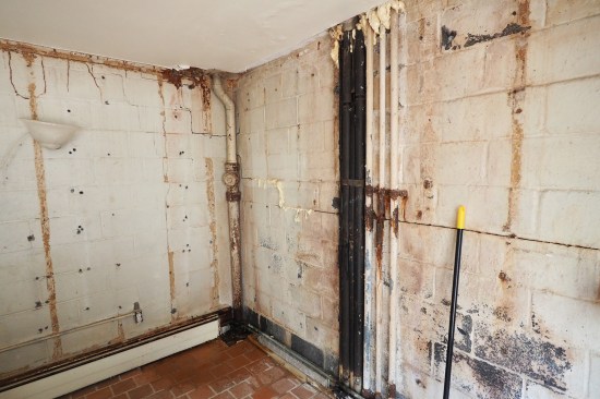 Cracked and leaky block retaining walls were revealed after removing termite-damaged framing and moldy drywall.
