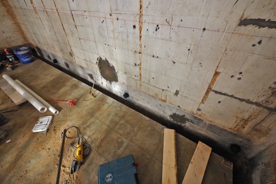 The existing slab was saw-cut in order to lock in the bottom of the liner wall. (The cut edge also allows room to drain the wet side of the drain board to daylight via two sub-slab PVC drainpipes—see illustration on main page.)