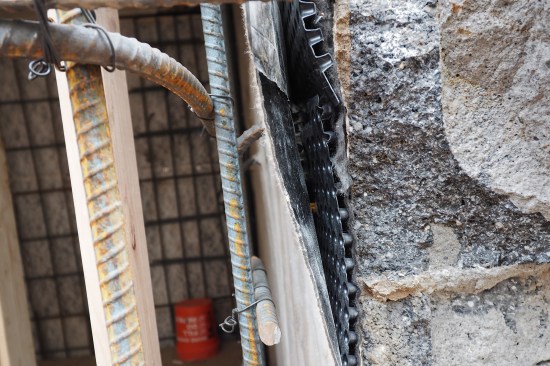 The waterproofing “system” consisted of a drain board and waterproofing sheet. Here, the dimpled drain board was installed up against the existing block wall with the dimple side “out” (against the block). The waterproofing sheet was then placed with the fleece side facing to the interior (wet concrete bonds to the membrane’s the fleece skin).