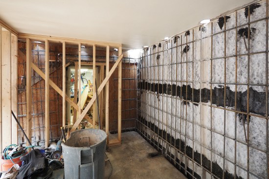 All seam laps, perimeter edges, and fasteners through the waterproofing membrane were sealed with a dark-colored waterproofing compound. With waterproofing in place, the rebar grid was installed. The grid was tied into the upper patio’s slab with rebar dowels placed through holes cored into the slab, and doweled into the block wall’s existing footing at the bottom.