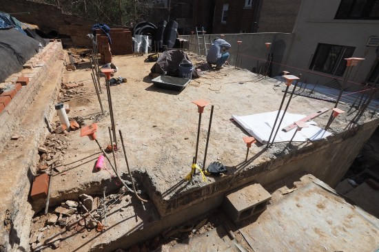 Rebar dowels wet-set into cored access holes help pin the existing slab to the top of the liner walls (the dowels flush-cut to slab later). To accommodate code-approved riser heights, the slab was cut away and a new landing was poured (lower left of photo).