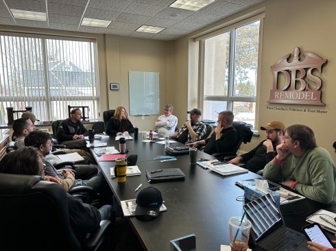 Lead carpenter meeting in DBS Remodel’s conference room. Their brand, “When cleanliness, politeness & trust matter” is on the wall (right-hand side of photo).