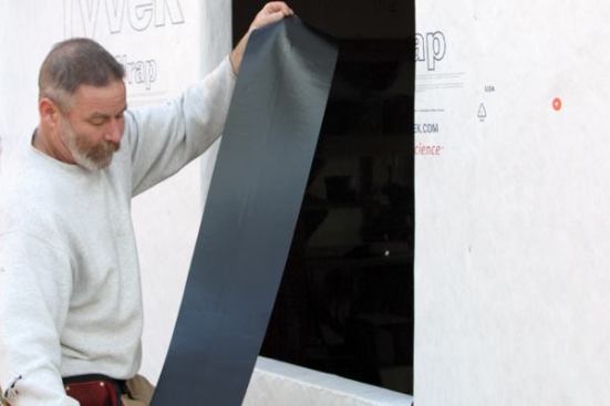 Flash the Sill
After taping the housewrap to the studs, I install the sill flashing membrane, cutting it a foot longer than the width of the opening so it can extend up the jambs 6 inches. 
Note: I prefer to use Tyvek FlexWrap, a butyl-based flashing membane. It has the self-healing characteristics of generic peel-and-stick but can also be stretched to form seamless corners.