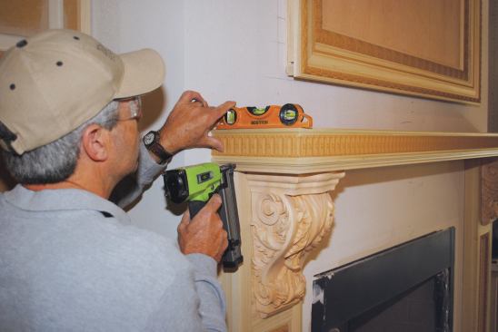 The first layer of the mantel shelf attaches to a length of plywood on top of the pilasters.