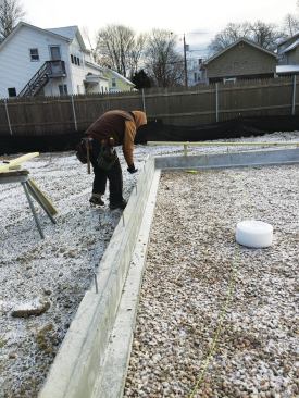 Concrete frost walls 10 inches thick extended 4 feet into the ground. A 6-inch-wide top surface would support and anchor the 2x6 exterior wall. The remaining thickness of the frost wall stepped down 8 inches to provide a 4-inch-wide shelf for the perimeter slab insulation.