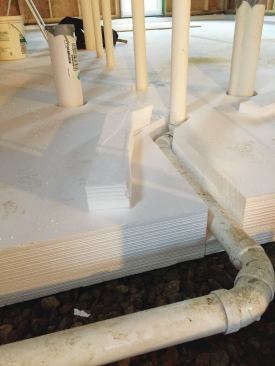 The plumber had left one pipe temporarily propped at the correct pitch above the level of the stone. When the foam panels went in, solid foam replaced the props and a channel was cut around the pipe.
