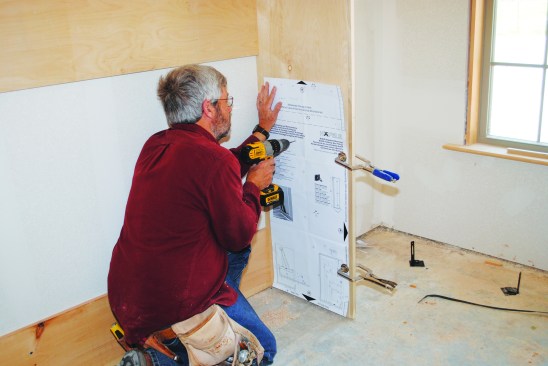 I clamped the paper template, provided by the hardware manufacturer, to the sides of the cabinet.As I drilled the holes, I took care not to blow out the plywood veneer on the outside. 