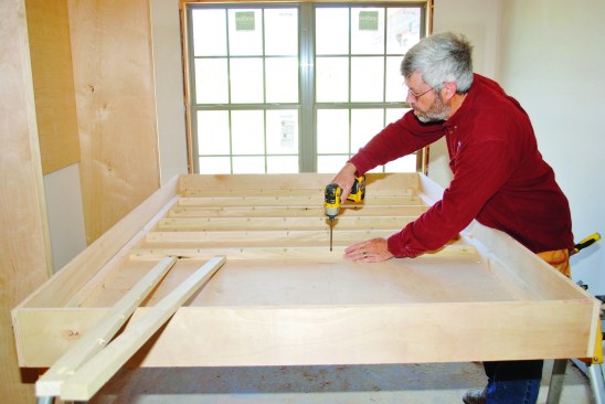 I nailed 1 1/2-inch by 1 1/2-inch strips along the inside edges of the platform, and then I screwed the slats to the bottom between the edge strips on 10-inch centers.