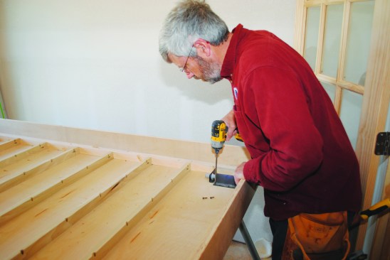 The hardware that holds the feet attaches to the bottom of the platform inside the box. 