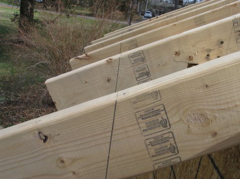 Rafter tails are installed long. Then the plumb cut is measured and marked on the first and last rafters. A chalk line snapped between those marks aligns the plumb cuts on the tails perfectly.