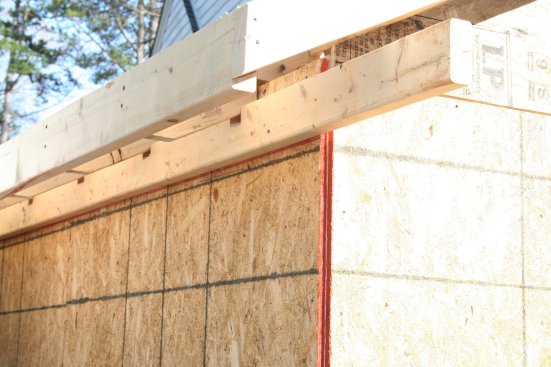 The ledger is left long and will be cut to length when the returns are built. Notches under the rafters allow the ledger stock to be full-dimension on the ends to better support the return framing.