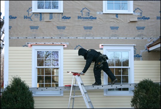 One facade at a time. In general, we replaced existing trim located closer to the ground, which was more prone to rotting; the home’s upper trim (the fascia, frieze, rake, and soffit) was in good shape. Working one facade at a time, we removed the existing siding and trim and replaced any rotted sheathing we came across. For the new weather-resistant barrier (WRB), we opted to use a drainable housewrap manufactured by Benjamin Obdyke called “HydroGap.” It comes with raised dots placed in serpentine pattern that provide a capillary break between the WRB and new siding, while also offering some ventilation. For the new siding, we installed HardiePlank lap siding, which we had pre-primed and painted. All the replacement trim was cellular PVC manufactured by Koma and the metal flashing was 16-ounce copper—we like copper because it’s long lasting and aesthetically pleasing and because you can solder the seam-work rather than relying on sealants to make watertight joints. Our painting subcontractor used Benjamin Moore Alkyd primer and Benjamin Moore Exterior for all the trim and siding finish.