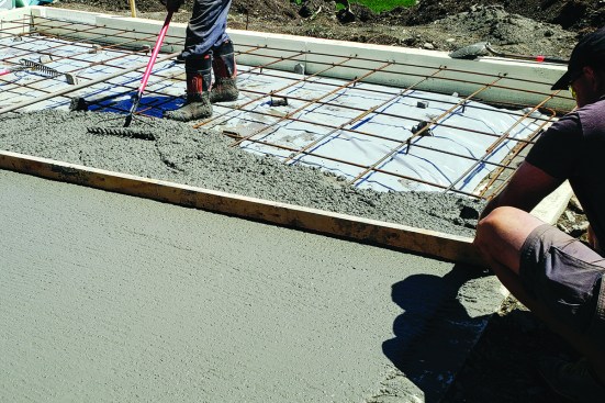Slab placement. The concrete crew places the slab, screeding the mix flush with the top of the forms.