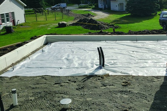 Then the crew spreads a layer of poly as a vapor barrier below the concrete slab. Vertical sections of rebar will tie into the rebar grid for the slab.