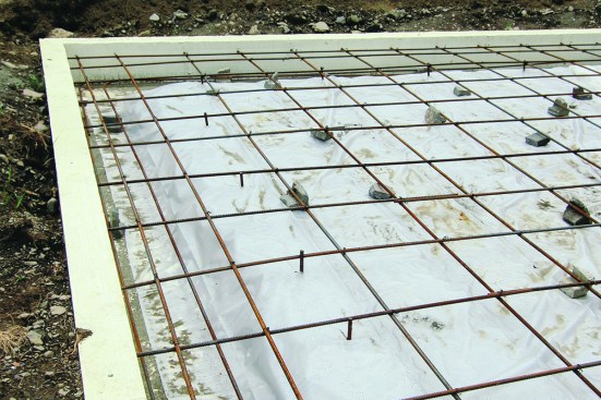 Each intersection is wire-tied together and anchored to the vertical rebar sections. An additional layer of rebar below the main layer reinforces the built-up edge of the slab.