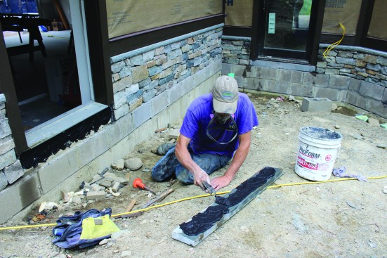 A layer of mortar is spread on the back of the damp toekick.