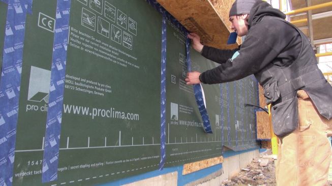 While taping the staple lines in the membrane, the crew also tapes the joints where the window bucks meet the membrane on the wall.