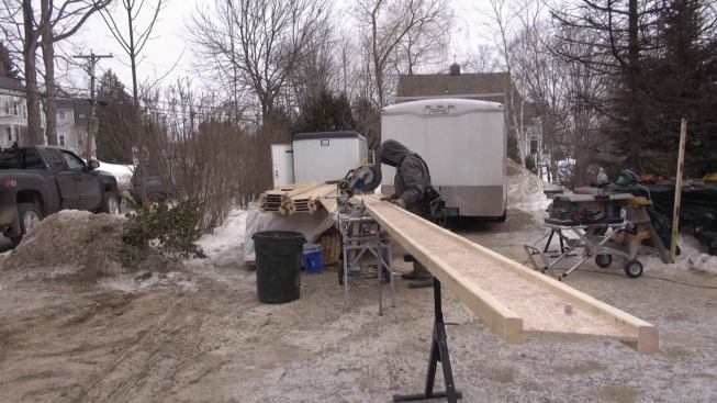 The crew uses a radial arm saw to cut wood I-joists to match the roof angle.