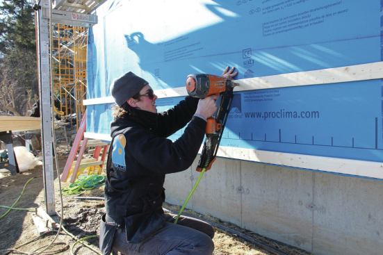 The crew applies horizontal strapping over the Solitex Mento fabric.