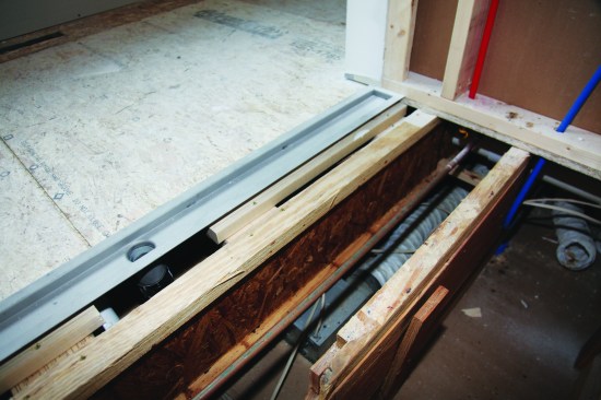 In the large shower, part of an I-joist  was cut out to accommodate the new drain, and a new joist was fished in next to it. 