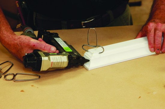 Yellow glue provides some wiggle room for aligniing the miters on the crown molding. Hold them in place with spring-loaded miter clamps while securing the molding with 1-inch 23-gauge pins. 