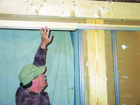 The header track for the pocket door is supported by split studs—thin strips of wood lined with metal. After making sure that the header track fit over the nails, I laid out the positions of the two split studs, marking their positions on the header track and on the floor.