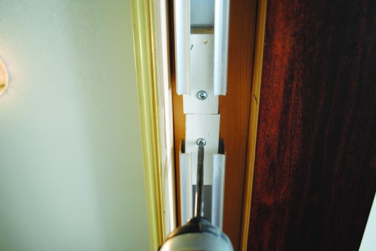 Wooden blocks ripped out of 1-by poplar were screwed in at both ends of the tracks as well as in the middle to act as stops to prevent the rollers from dropping out of the track in the middle, and to keep the doors from hitting the trim returns at the ends.