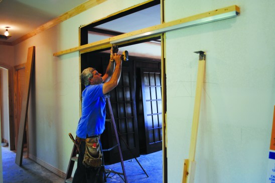 The track sections were screwed to the split header flush with both ends and flush with the outside edge of the track. This positioning left enough space for the doors to clear the jamb casing when they opened and closed.