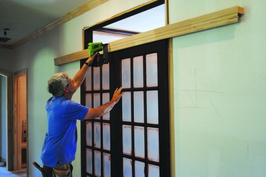 To hide the track assembly, the author nailed trim to the header. Almost any kind of trim could be used, but for this project, a length of inverted baseboard created the first layer.