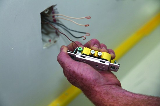 Then, he catches the end of the wire on the metal tab next to the screw and rotates the device to close the loop for a better connection.