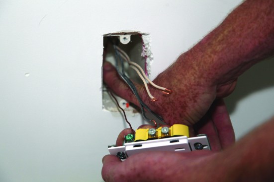 He then tucks the ground conductor into one of the back corners of the electrical box.
