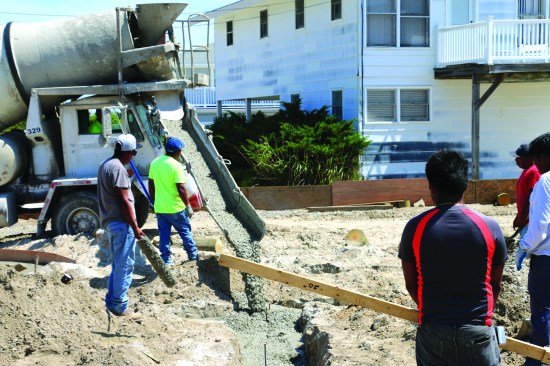 A concrete truck places mix for each beam while the crew moves the mix around quickly to avoid cold joints in the grade beams.