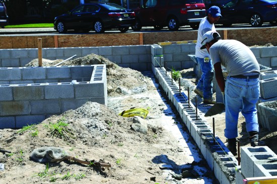 After letting the beams cure, the masons build short foundation walls. Lengths
of rebar are drilled and epoxied to tie the block to the grade beams, and the concrete block is then fully grouted.