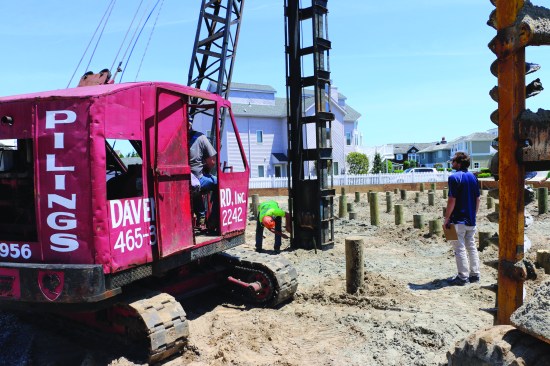 When all the pilings are in their holes, the crew attaches a sled with a 1-ton driving hammer to the crane. The crane positions the sled over each piling and a crew member marks 6-inch increments on the sled to monitor how deep the piling travels with each hit.
