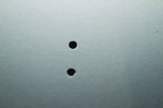 The top screw is driven properly, but the bottom screw has broken the paper around the screw head.