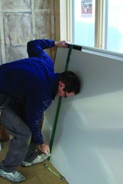 To cut a sheet of drywall to length, set the T-square at the measurement and score along it with a sharp utility knife.
