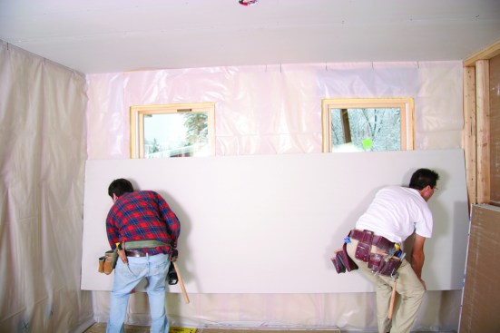 You can cut out for windows before lifting, but it’s quicker to first lift and fasten the sheet in place and then cut around the frames with a router.