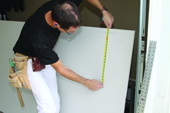 Score a rip by pulling the utility knife and the bottom of your measuring tape along the sheet.