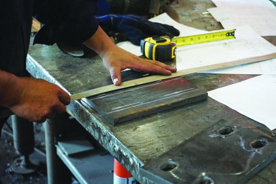 The steps for basic metal-shop work are set by standards to ensure consistent work throughout the industry. Here, a fabricator follows the standard procedures for laying out bolt-hole positions.