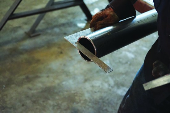 Welding a connection plate onto a column starts with checking the cut for square.