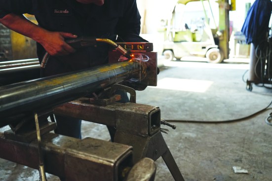 With the plate positioned at the layout marks, the fabricator tack welds the plate to the column in four places.