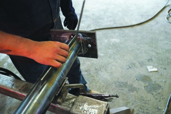 Before completing the weld, he makes sure the plate is square to the column on one side.