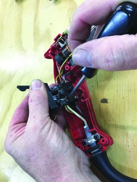 On the opposite side of the switch, he backs off screws that hold the wires in place on that side.