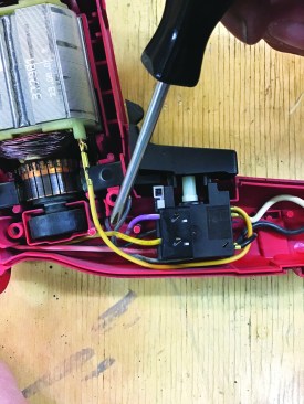 Checking against the photos he had taken earlier, he repositions the switch and makes sure the wires are routed through the handle without being pinched.