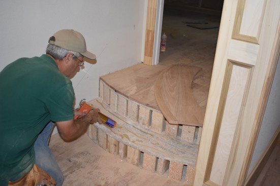 When all the cutting is finished, the author applies construction adhesive to the rough tread.
