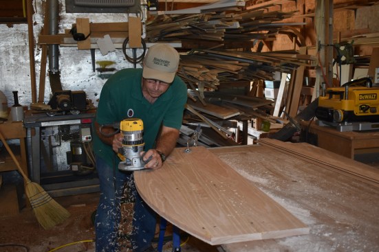 The author flips the board over completes the curved cut using a bearing-guided bit to follow the initial router cut, leaving a smooth fair curve at the proper radius.
