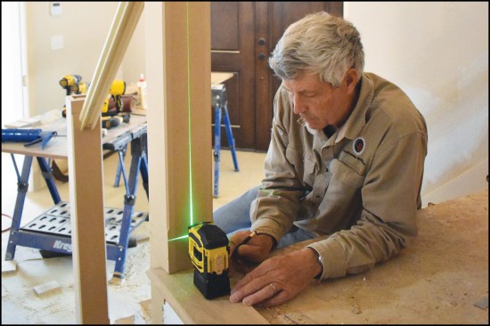 The author uses a laser to locate and mark the centerline for a new handrail during the stair makeover project.